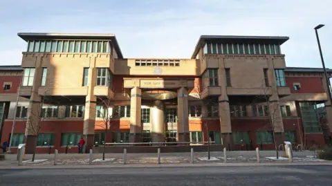 The exterior of Sheffield Crown Court features red brick and ashlar stone and a three-storeys high central bay