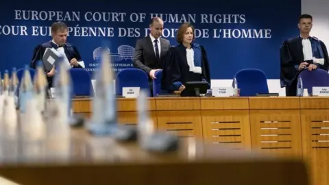Getty Images Irish chairman of ECHR, Siofra O'Leary (C) and Slovenia judge Marko Bosnjak (R) arrive for the European Court of Human Rights hearing in two climate change cases involving France and Switzerland, on March 29, 2023 in Strasbourg, eastern France.