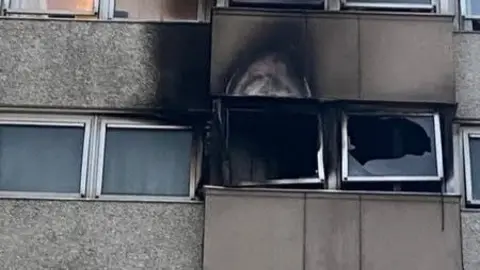 Essex Fire and Rescue Service Fire-damaged windows and charred brickwork show the exterior of a flat after a blaze broke out on the fourth flour of the 12-storey tower.