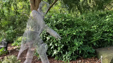A wire sculpture of a historical man stands in a public garden in York.
