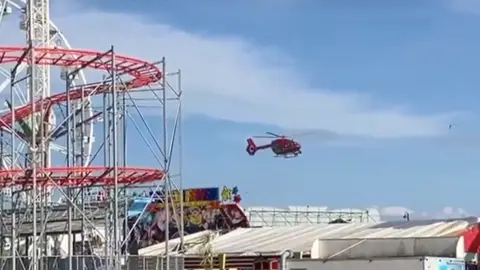 Visit Barry Island A red air ambulance flying above Barry Island Pleasure Beach