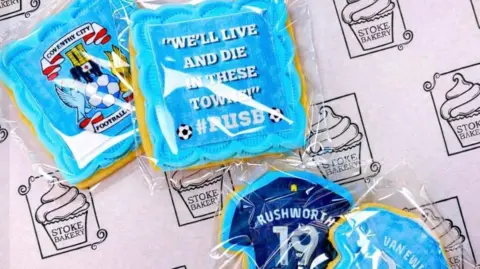 Gemma Glover Decorated biscuits with football‑themed designs and messages are displayed on branded bakery paper.
