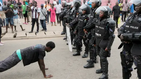 Francis Kokoroko/Reuters A protester doing a press-up in front of police in Accra, Ghana - Saturday 23 September 2023