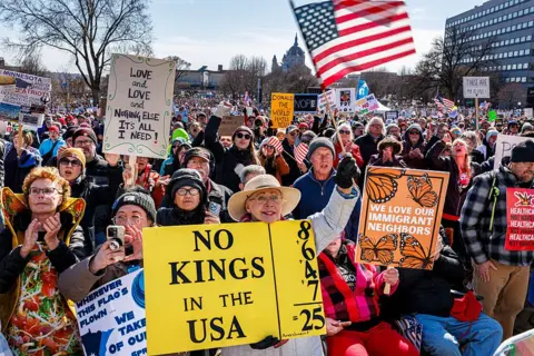 Getty Images People hold signs and flags outside the Minnesota State Capitol in Saint Paul. They are rallying against the Trump administration. 