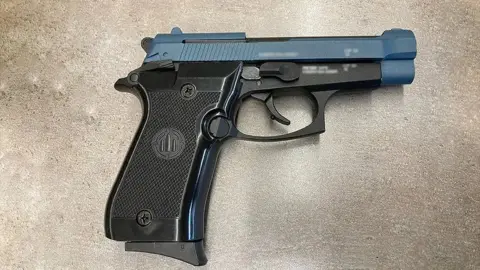 A black and blue handgun laid on a grey surface