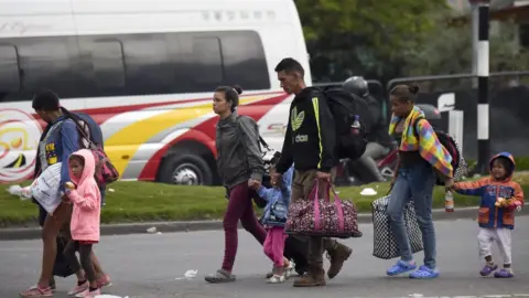 Getty Images Venezuelan migrants walk out a bus terminal heading to an improvised camp in Bogota