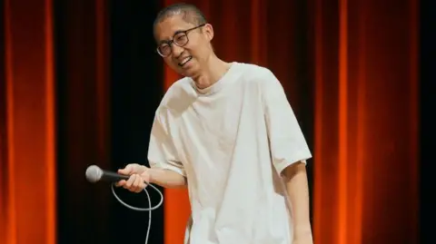 Supplied Chizi performs on stage in Taipei in April 2026, wearing a white oversized T shirt and a pair of glasses.