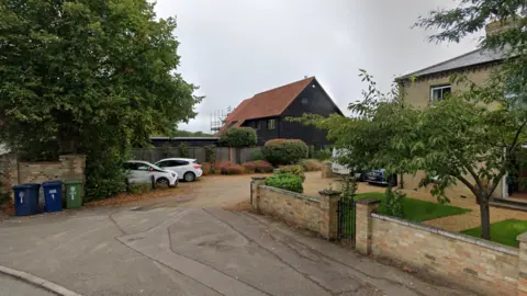 Google Primes Corner in Histon showing a yellow stone house, a gravel driveway and a barn-style house in the background