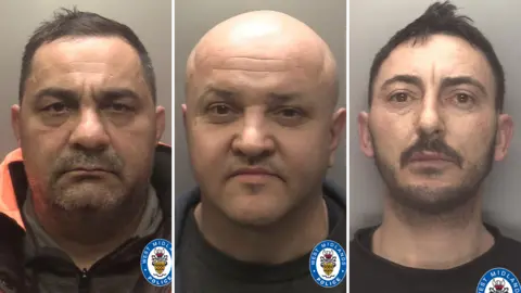 Three men pictured in mug shots. Aldafin Poenaru has short black hair, dark stubble around his mouth ad wears a black and orange hood jacket. Sorin Condrache is bald and wears grey shirt, while Marian Agarlita has spikey black hair, a black moustache and black beard. He is wearing a black tshirt.
