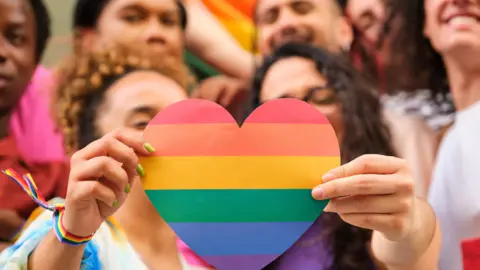 Getty Images Two people hold up a heart with bright and varied colours