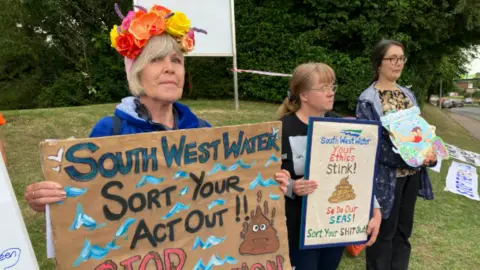 BBC Campaigners outside Penisula House in Exeter holding placards criticising South West Water