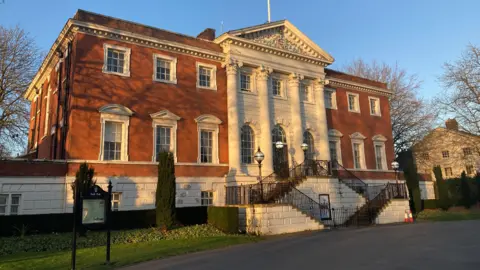 Warrington Town Hall, a large Georgian building built in the Palladian style. It is two storeys high and has four round columns in the middle.