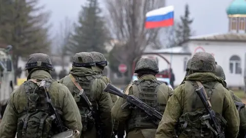 Getty Images Russian soldiers patrol the area surrounding the Ukrainian military unit in Perevalnoye, outside Simferopol, in 2014
