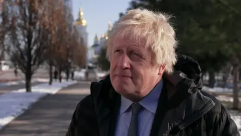 Former UK Prime Minister Boris Johnson being interviewed by the BBC in Kyiv. He is standing on a road with St Michael's Golden-Domed Monastery in the background