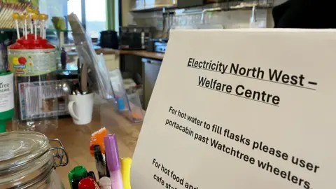 A sign at the Watchtree Nature Reserve Cafe with an Electricity North West Welfare Centre sign which gives details of how to access hot water and hot food. 