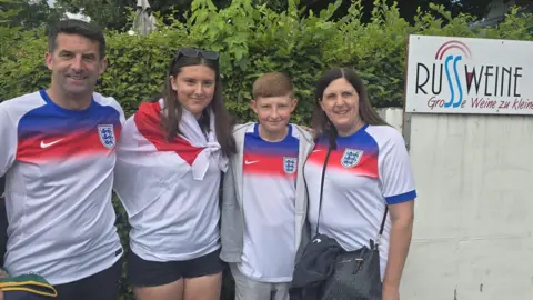 Family Kevin, Amelia, Ethan and Kelly are standing in a line wearing football tops.