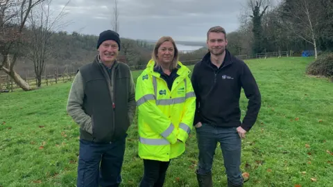 Two men and a woman standing in field