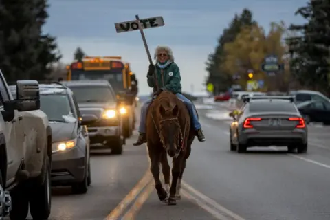 Natalie Behring/Getty Images Vancie Tuner and her horse Clementine, beloved residents of Teton County, rally people on Main St. to vote on November 5, 2024 in Driggs, Idaho. 