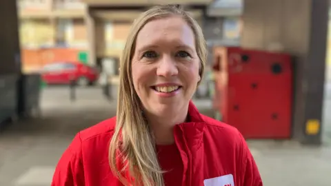 Emily Robinson, from London Sport, in a red jacket and red t-shirt.