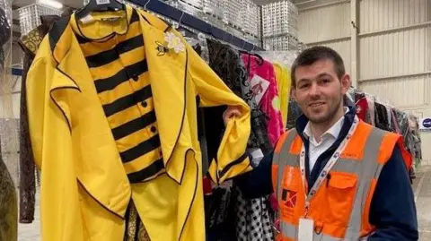 Site manager Karl Smith in orange high-viz jacket with some of the costumes ready for dispatch  