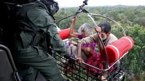 Reuters People are airlifted by the Indian Navy soldiers during a rescue operation at a flooded area in the southern state of Kerala, India, 17 August 2018