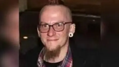 Lincolnshire Police Adrian Whiting wearing glasses and a red, white and blue checked shirt