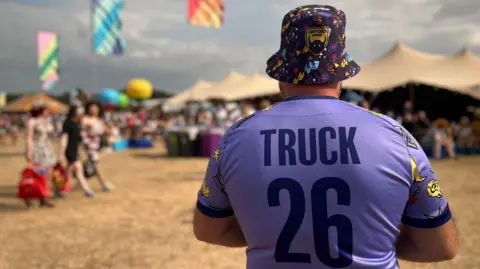 A man wearing a purple shirt with Truck 26 printed on the back.
