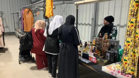 Elizabeth Baines / BBC Three ladies line up outside a stall at Huddersfield's new temporary market
