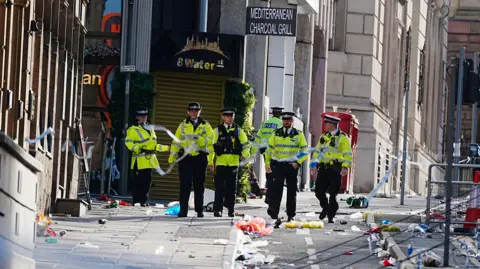 Water Street covered in debris as six police officers can be seen close to the police cordon after the incident on 26 May