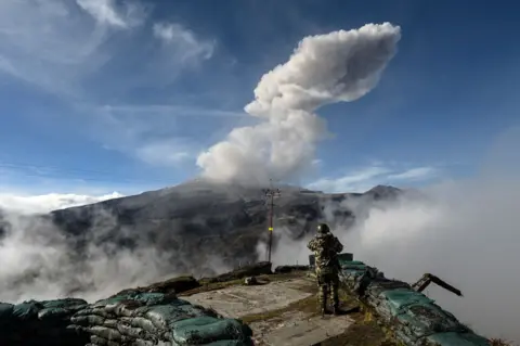 JOAQUIN SARMIENTO/AFP Colombian soldier watches the Nevado del Ruiz volcano as it emits a cloud of ash