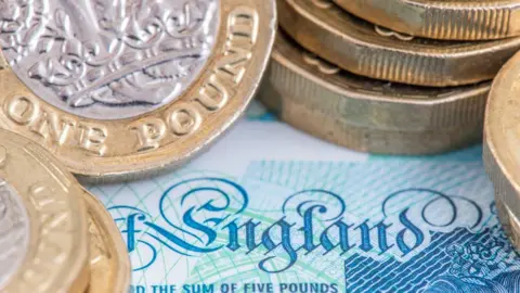 Getty Images The word "England" as depicted on an English £5 note, surrounded by stacks of newly minted pound coins