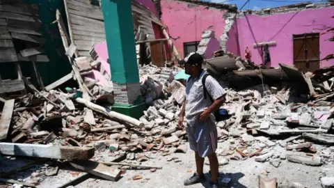 AFP/GETTY Man surveys damage to collapsed houses