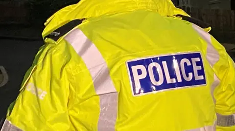 The back of a man wearing a police jacket at night time