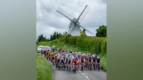 Ride London cyclists riding along a country road, with the backdrop of a white windmill