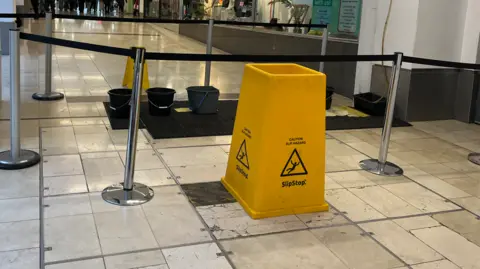 Buckets and yellow wet floor signs inside the Derbion shopping centre