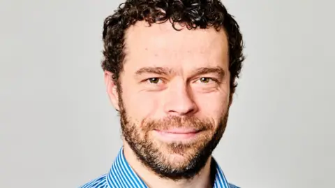 The Newcastle upon Tyne Hospitals NHS Foundation Trust Dr Richard Holliday. He has brown hair and a beard.