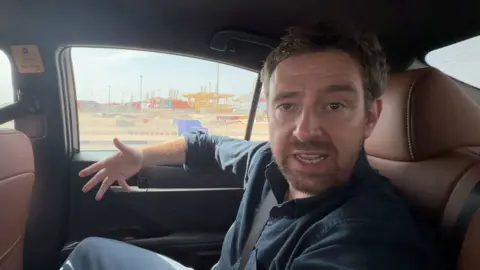 BBC correspondent Nick Beake sat inside a car driving through Dubai's Port of Jebel Ali