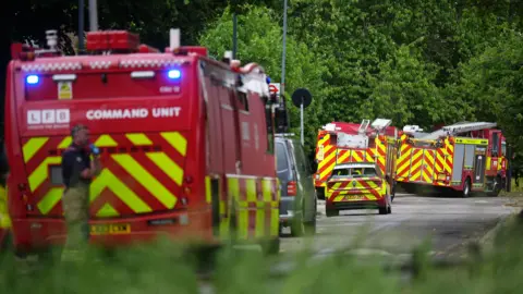 PA Media ambulances and an emergency services car follow each other along a road