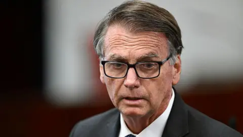Headshot of Jair Bolsonaro wearing glasses as he is questioned in court