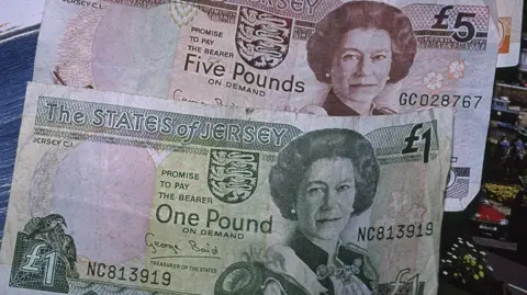 An old Jersey £1 and £5 note from 1989 showing the late Queen on the right and two birds of the left of the £1 note.