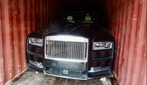 Essex Police A black luxury vehicle inside a red shipping container