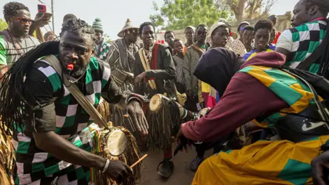 Getty Images Baye Fall followers, some in colourful patchwork clothes, drumming and whistling on a street in Diourbel, Senegal