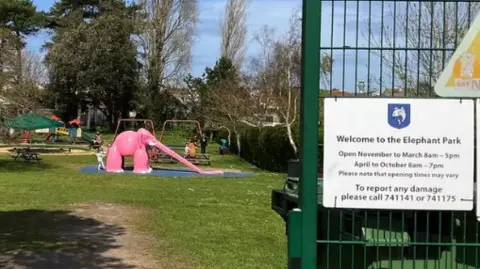 An image of the Elephant Park in St Brelade, including a grassy area and a pink elephant with a slide for a trunk
