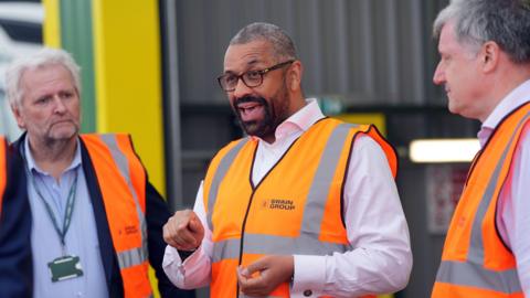 Home Secretary James Cleverly dons a hi-vis vest during a visit to Swain Group in Rochester, Kent.