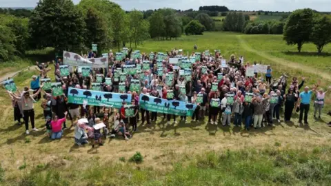 LDRS Hundreds of protestors stood together at the former golf course. Many are holding banner that read 'Keep our old golf course green'. 