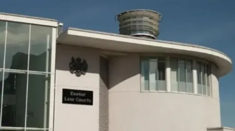 The outside of a white modern court building with the words Exeter Law Courts and the judiciary coat of arms on the wall.