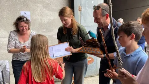 BBC A woman presenting an award to schoolchildren