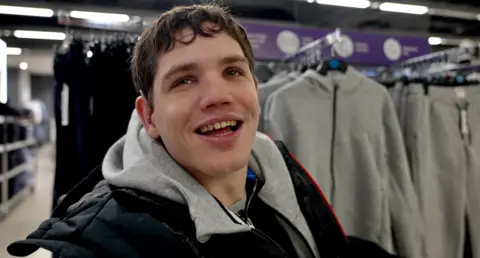 Elliot Caswell, model with cerebral palsy, in Primark beside the accessible clothing range