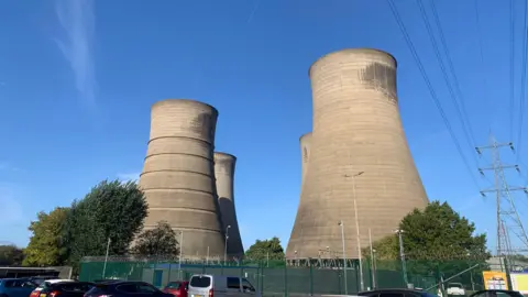 West Burton Power station - four cooling towers seen from ground level, against a blue sky