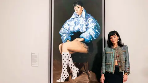 Lily Allen standing in front of her portrait at the National Portrait Gallery Copyright
